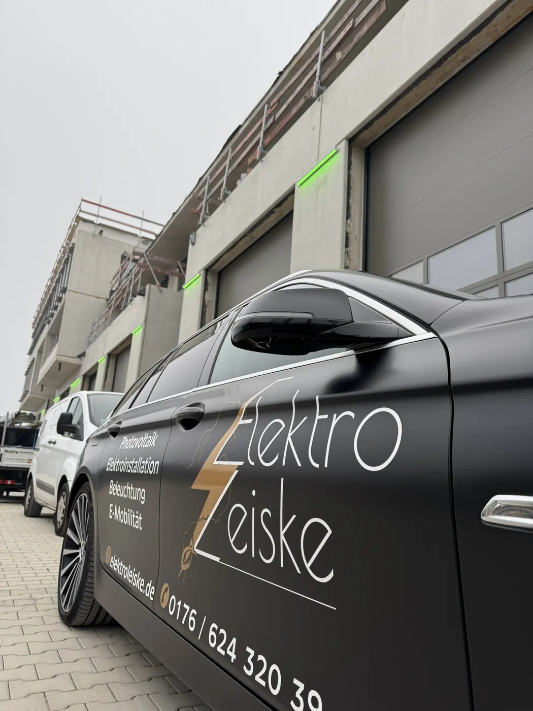 Firmenwagen von Elektro Leiske mit Logo vor einem Gewerbeneubau
