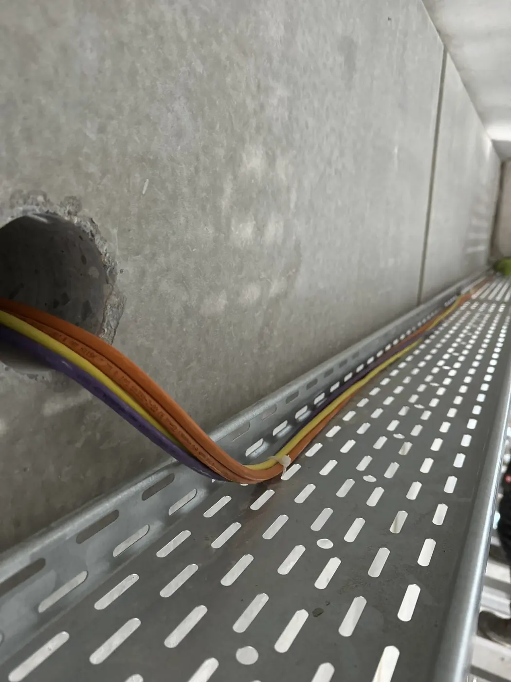 Kabeltrasse mit neu verlegten Leitungen an einer Betonwand