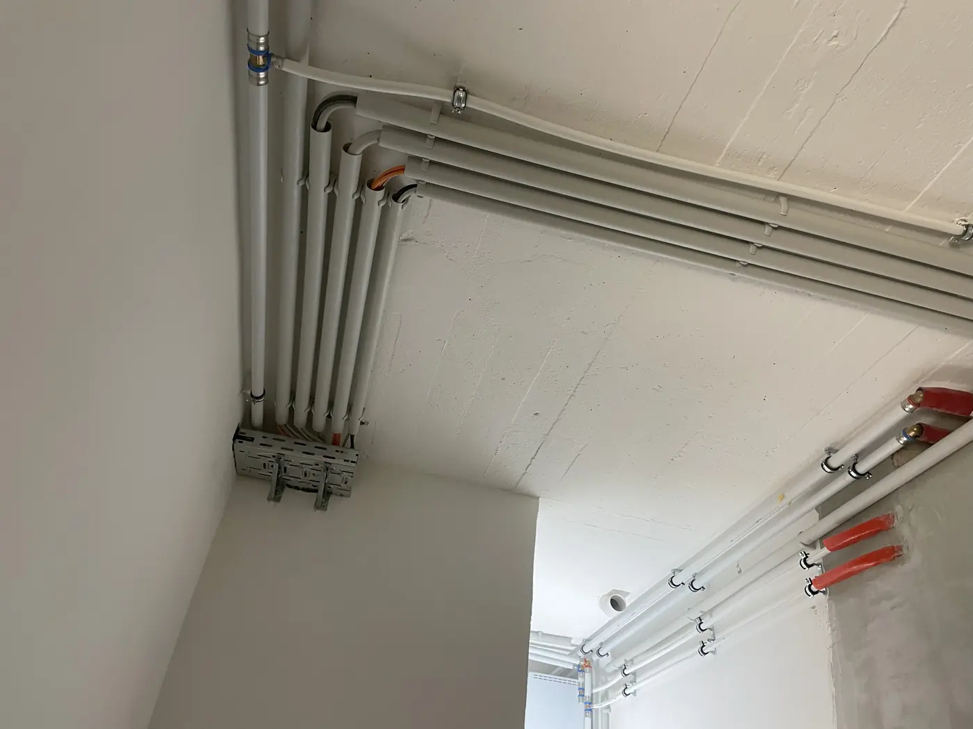 Parallel verlegte Leerrohre an Wand und Decke eines Neubaus