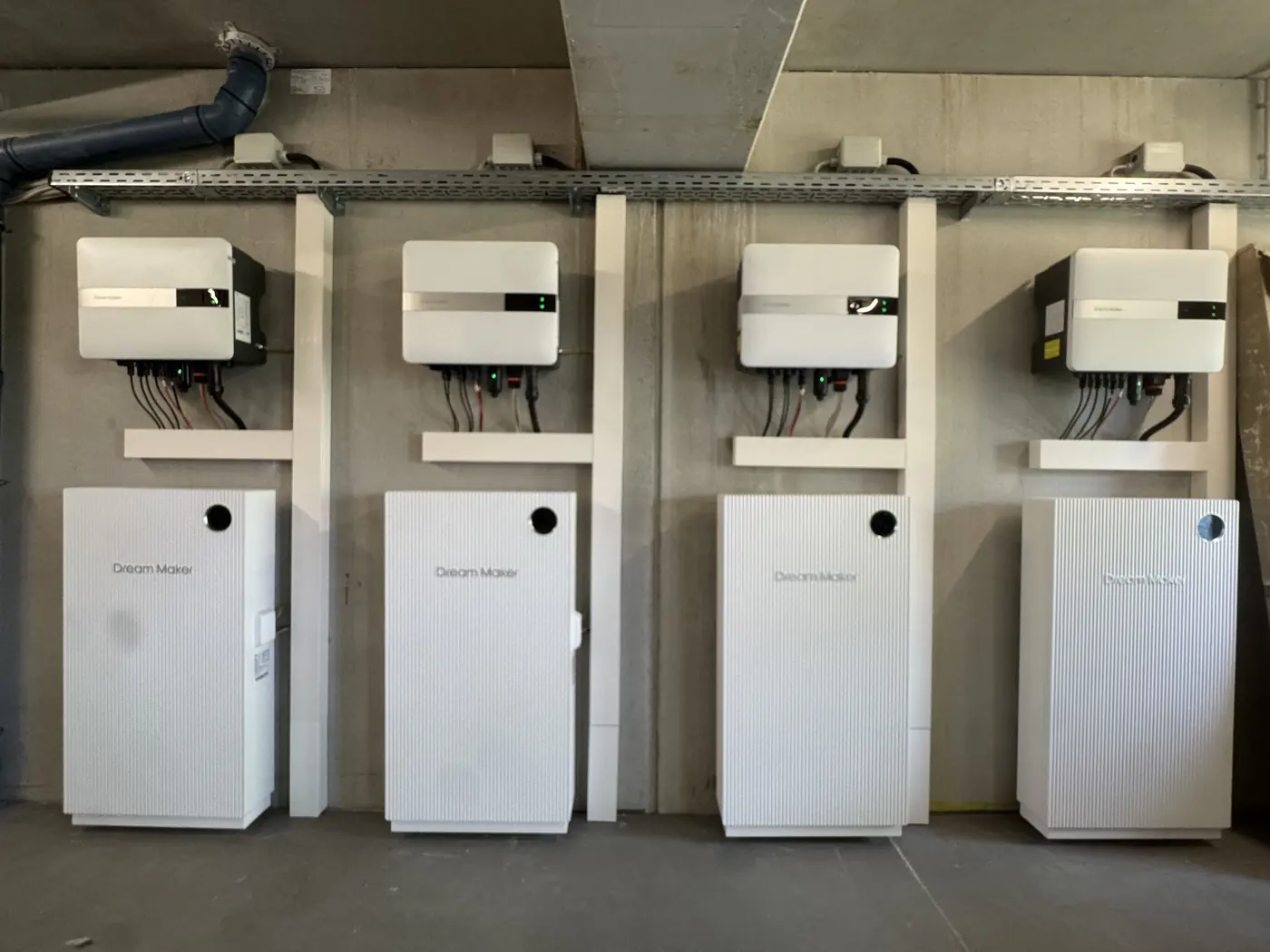 Vier Wechselrichter mit Batteriespeichern an einer Betonwand, montiert von Elektro Leiske für eine 80-kW-PV-Anlage